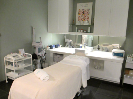 A clean and organized spa treatment room with a massage table and various skincare equipment.