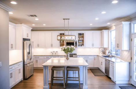 Modern kitchen with white cabinetry, stainless steel appliances, and a central island with two stools.